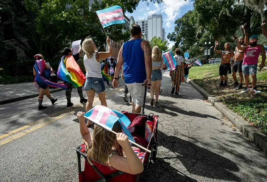 Participants wave flags at the National Trans Visibility March in downtown Orlando, Florida – Photo by Ronen Tivony / Sipa USA / AP