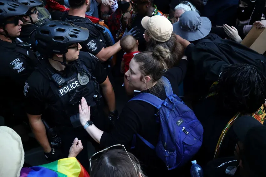 Protestors keep woman with baby safe and attempt to de-escalate when cops arrive. Photo by Hannah Saunders.